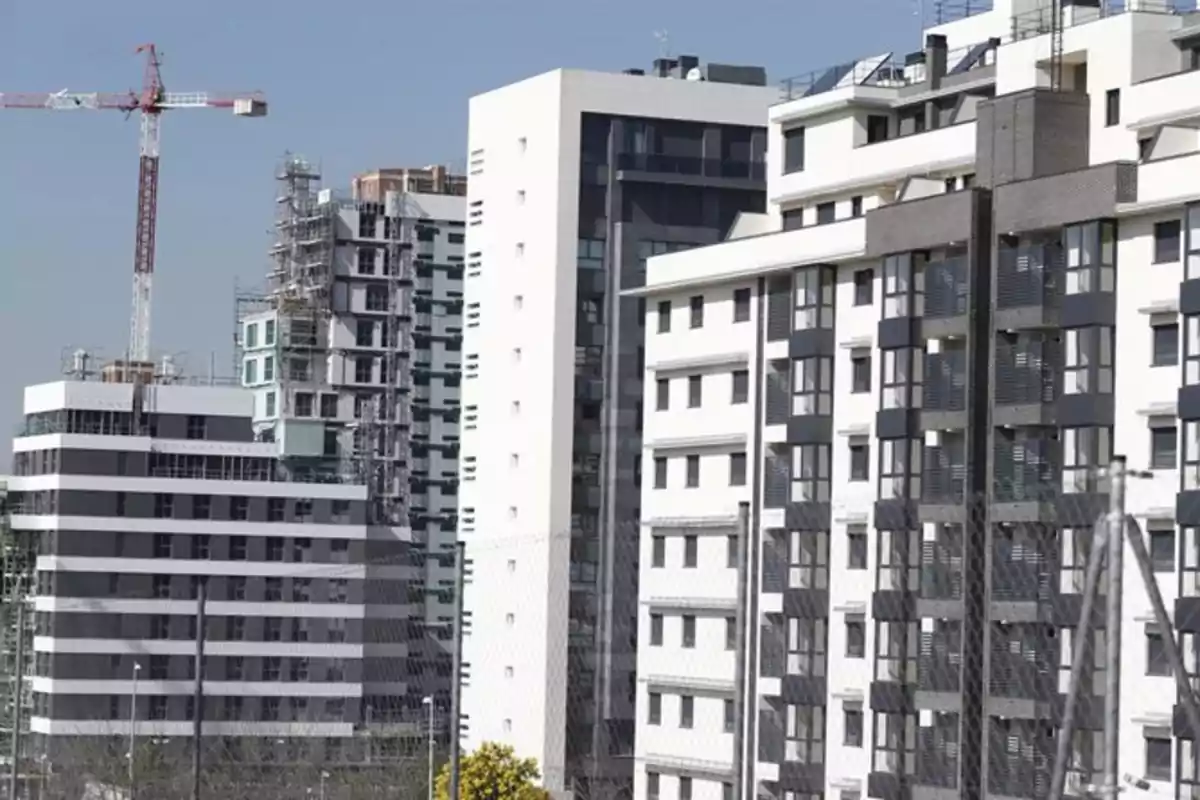 Varios edificios modernos de departamentos en construcción con una grúa al fondo bajo un cielo despejado Varios edificios modernos de departamentos en construcción con una grúa al fondo bajo un cielo despejado