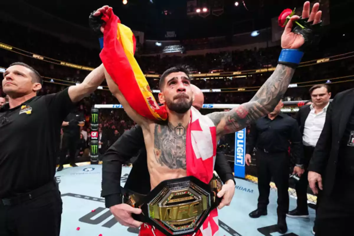 Un luchador de artes marciales mixtas celebra su victoria en el octágono con un cinturón de campeón, una bandera sobre los hombros y una rosa en la mano mientras el árbitro le levanta el brazo Un luchador de artes marciales mixtas celebra su victoria en el octágono con un cinturón de campeón, una bandera sobre los hombros y una rosa en la mano mientras el árbitro le levanta el brazo