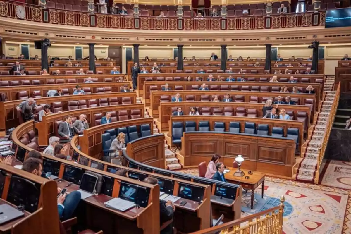 Vista del interior de un parlamento con varios escaños ocupados por personas durante una sesión legislativa Vista del interior de un parlamento con varios escaños ocupados por personas durante una sesión legislativa