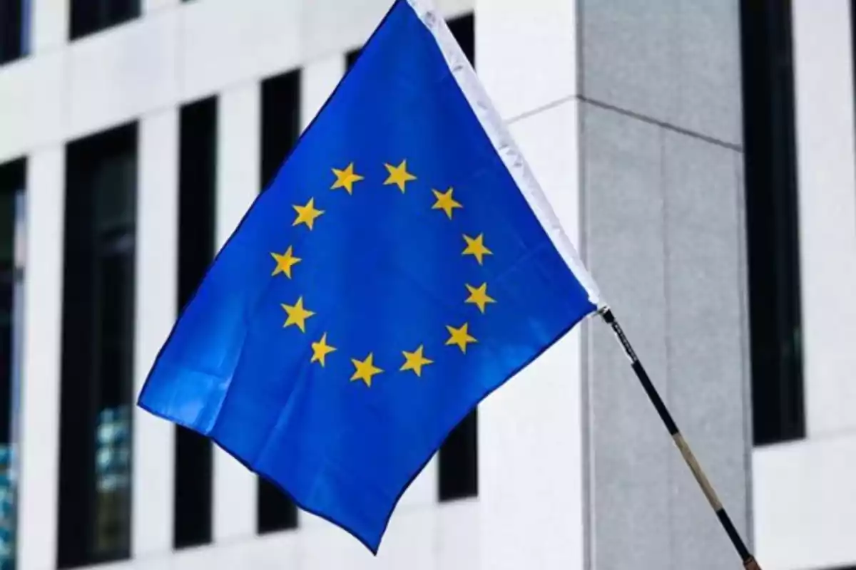 Bandera de la Unión Europea ondeando frente a un edificio moderno
