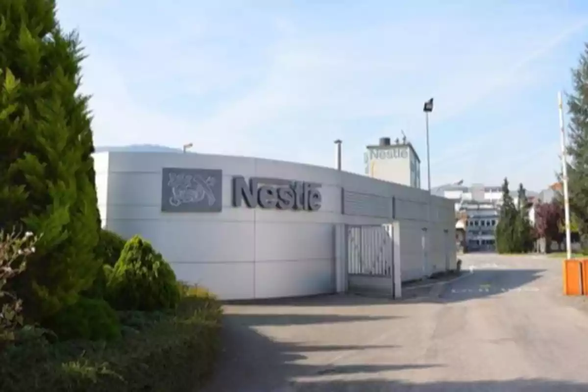 Fachada de una planta industrial de Nestlé con árboles y un camino de acceso Fachada de una planta industrial de Nestlé con árboles y un camino de acceso