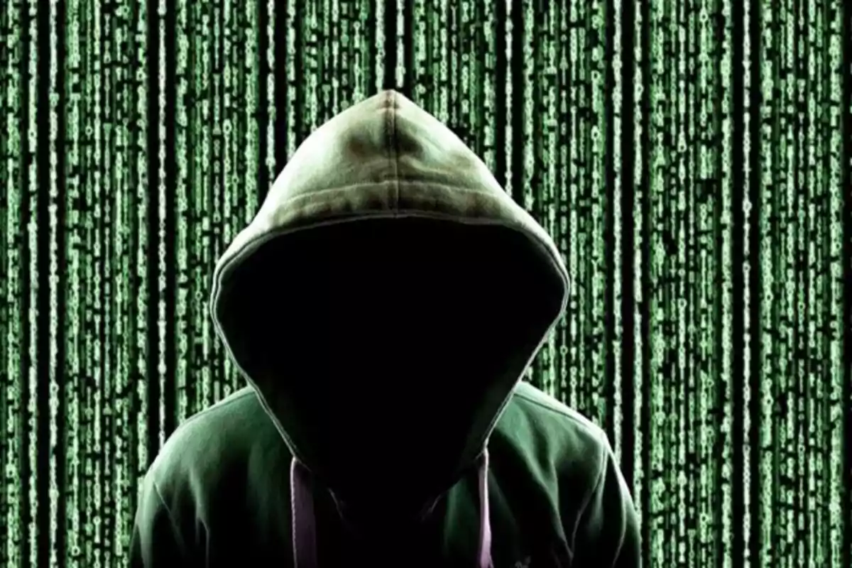 Persona con sudadera con capucha oscura frente a un fondo de código digital verde Persona con sudadera con capucha oscura frente a un fondo de código digital verde