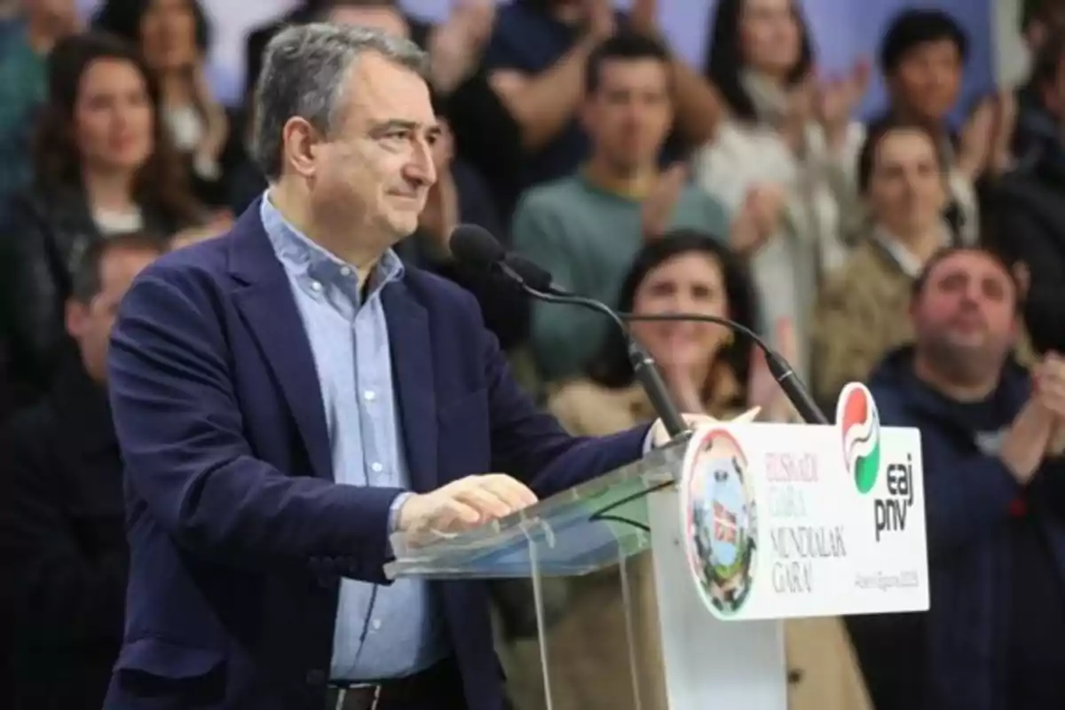 Hombre de cabello canoso hablando en un atril con micrófono frente a una audiencia que aplaude en un evento del partido EAJ PNV Hombre de cabello canoso hablando en un atril con micrófono frente a una audiencia que aplaude en un evento del partido EAJ PNV