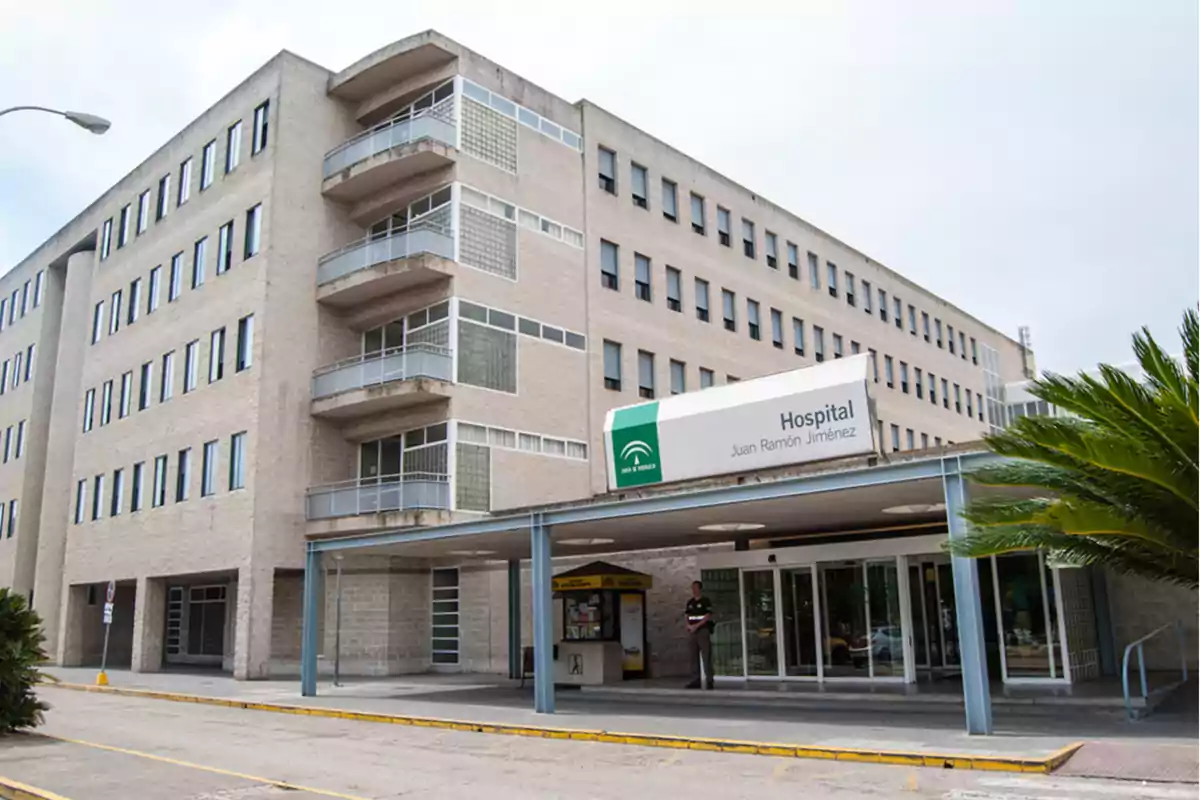 Fachada principal del Hospital Juan Ramón Jiménez con entrada cubierta y un hombre de pie junto a la puerta