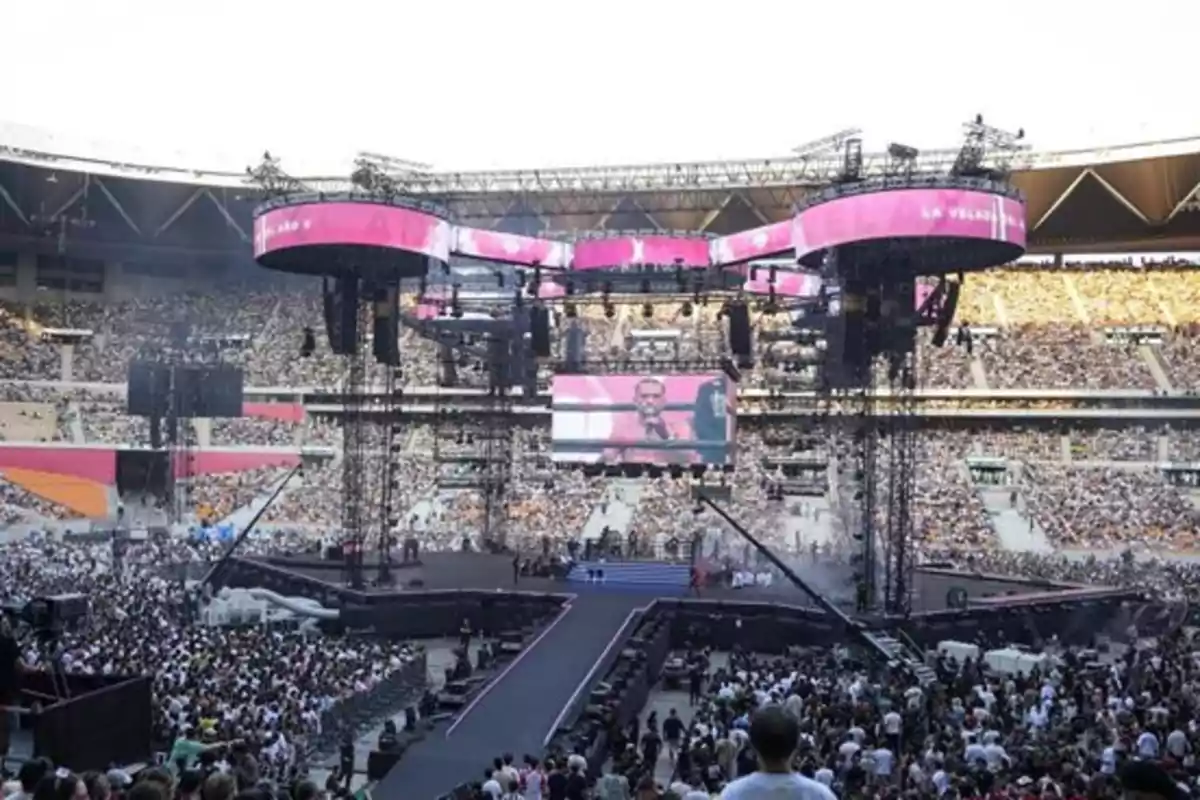 Estadio lleno de personas durante un concierto con un gran escenario y pantallas gigantes Estadio lleno de personas durante un concierto con un gran escenario y pantallas gigantes