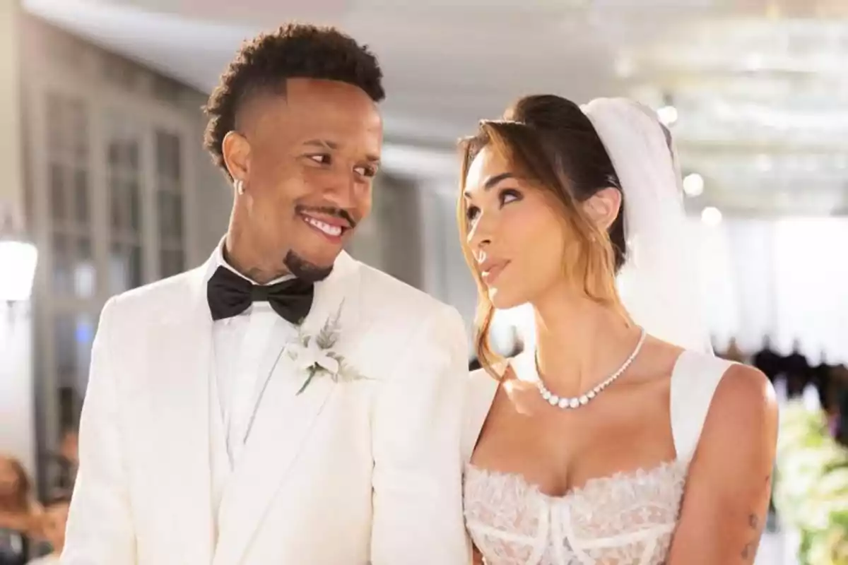 Pareja vestida de novios mirándose con una expresión feliz durante su boda