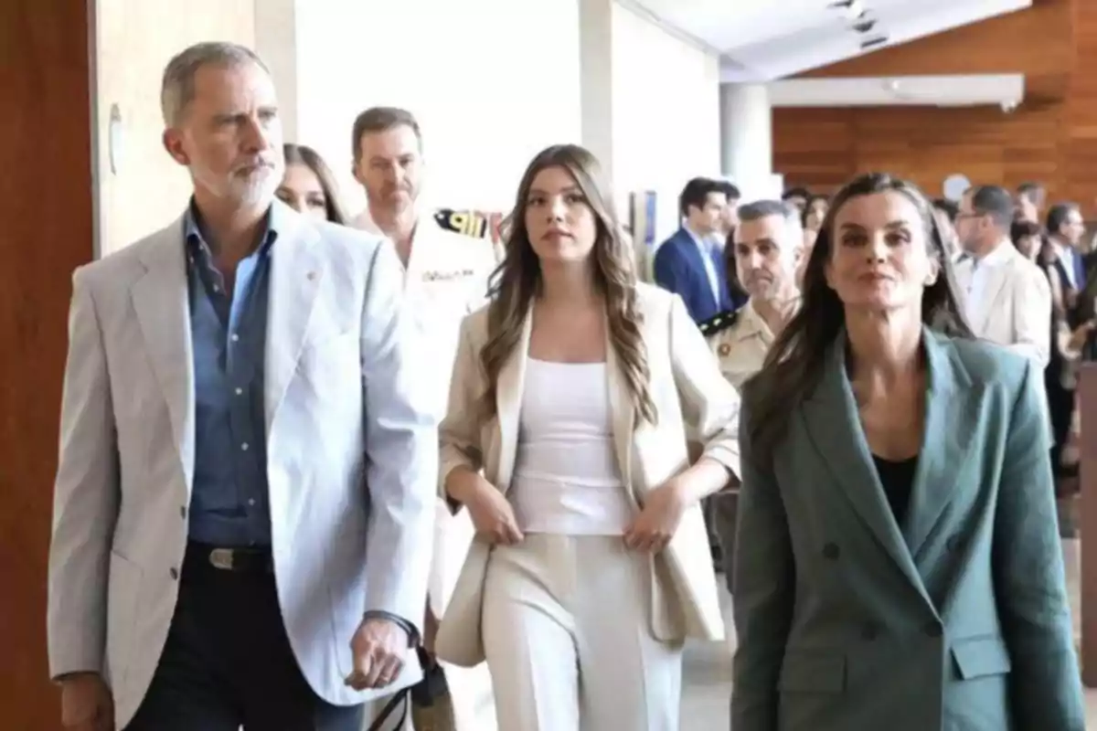 La Familia Real vestidos de manera formal caminan por un pasillo acompañadas de otras personas en el fondo La Familia Real vestidos de manera formal caminan por un pasillo acompañadas de otras personas en el fondo