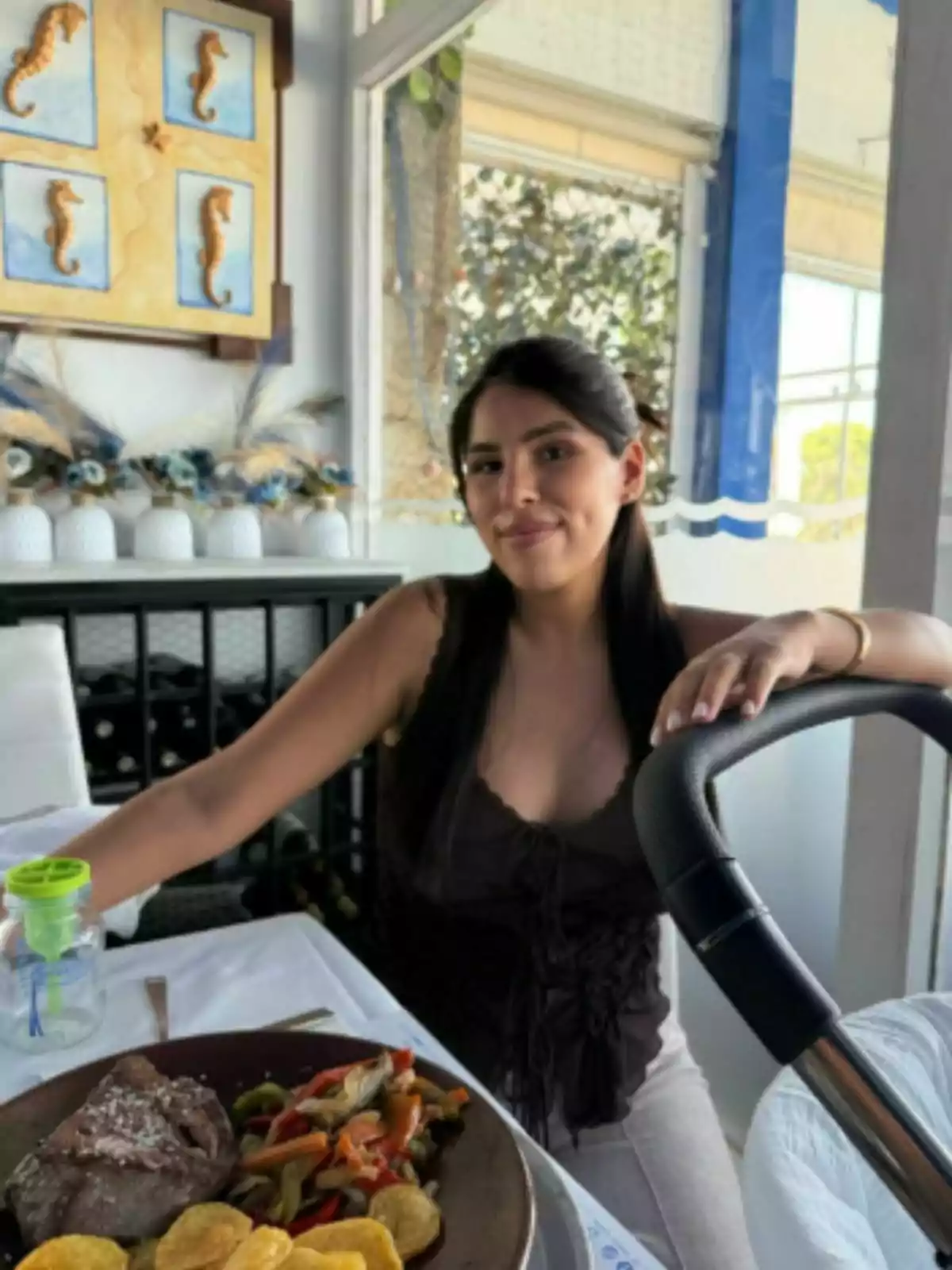 Isa Pantoja sentada en un restaurante junto a una mesa con comida y un cochecito de bebé al frente. Isa Pantoja sentada en un restaurante junto a una mesa con comida y un cochecito de bebé al frente.