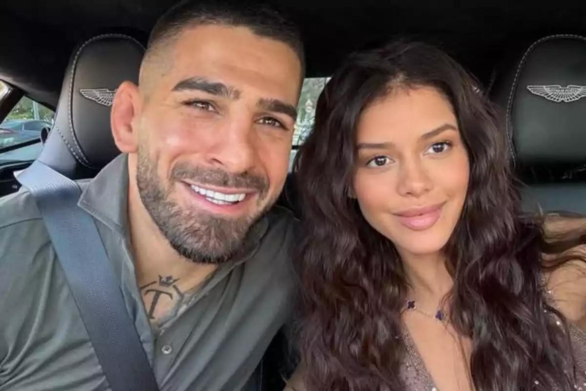 Pareja sentada en un auto sonriendo mientras se toman una selfie Pareja sentada en un auto sonriendo mientras se toman una selfie
