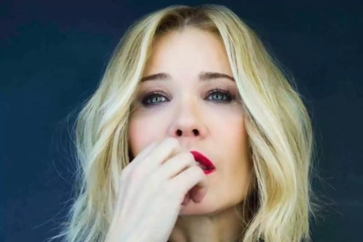 Mujer rubia con labios rojos y expresión pensativa mirando al frente