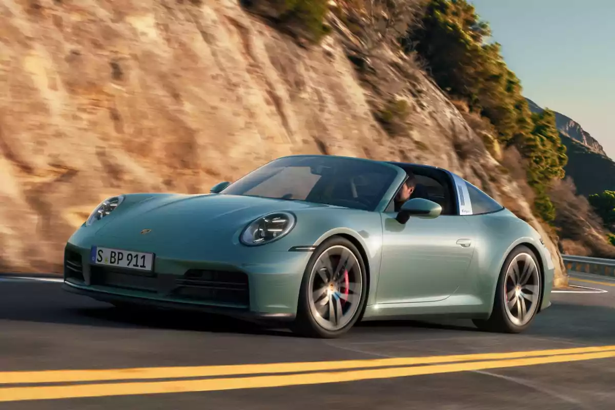 Auto 911 Carrera 4S color verde claro conduciendo por una carretera de montaña con fondo de rocas y vegetación