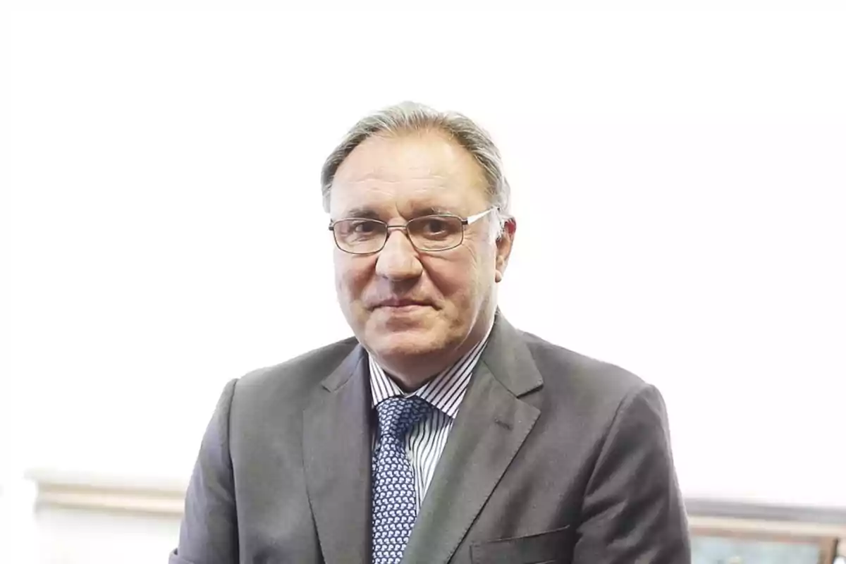 Hombre de mediana edad con gafas y traje formal posando frente a un fondo blanco Hombre de mediana edad con gafas y traje formal posando frente a un fondo blanco