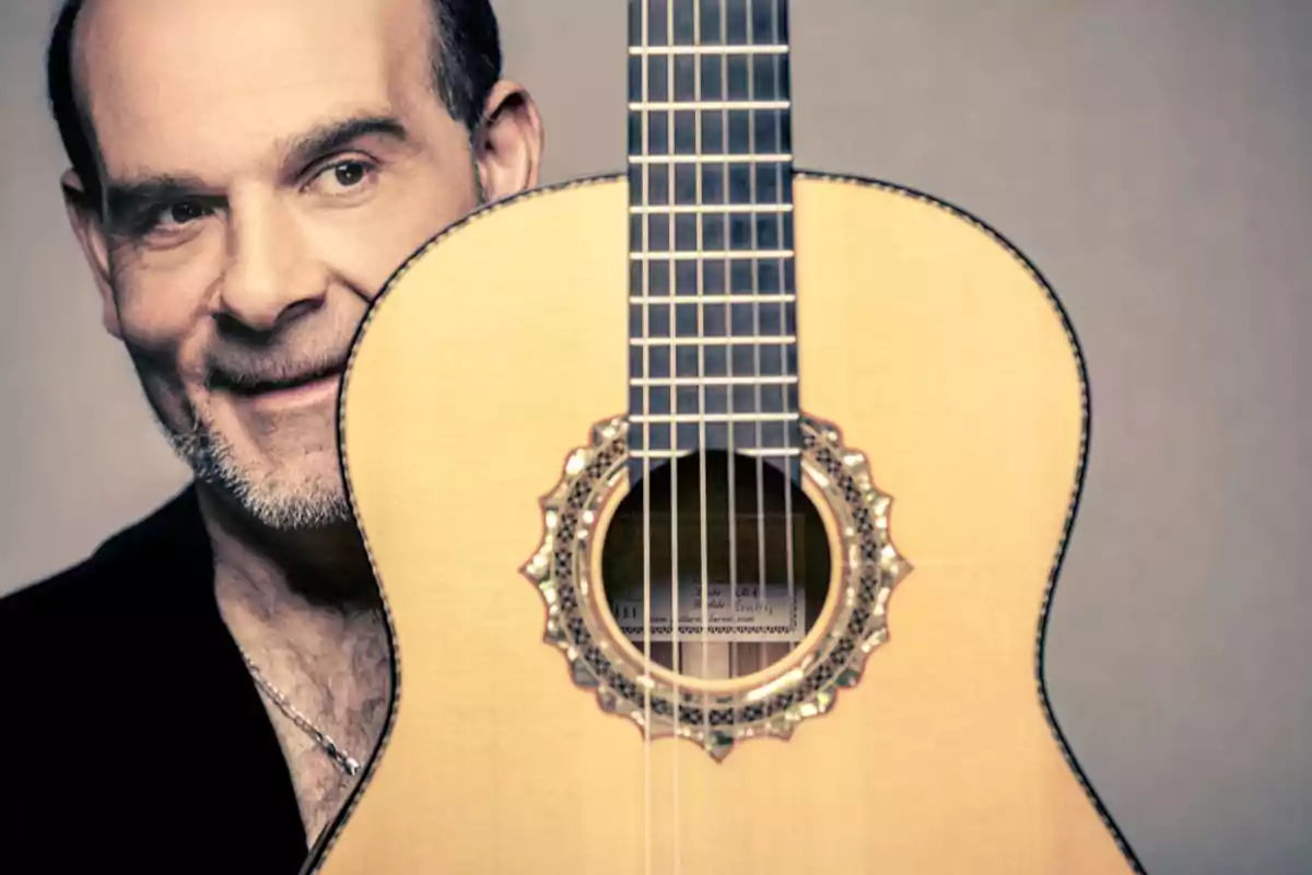 Hombre sonriente sosteniendo una guitarra flamenca que cubre parcialmente su rostro Hombre sonriente sosteniendo una guitarra flamenca que cubre parcialmente su rostro