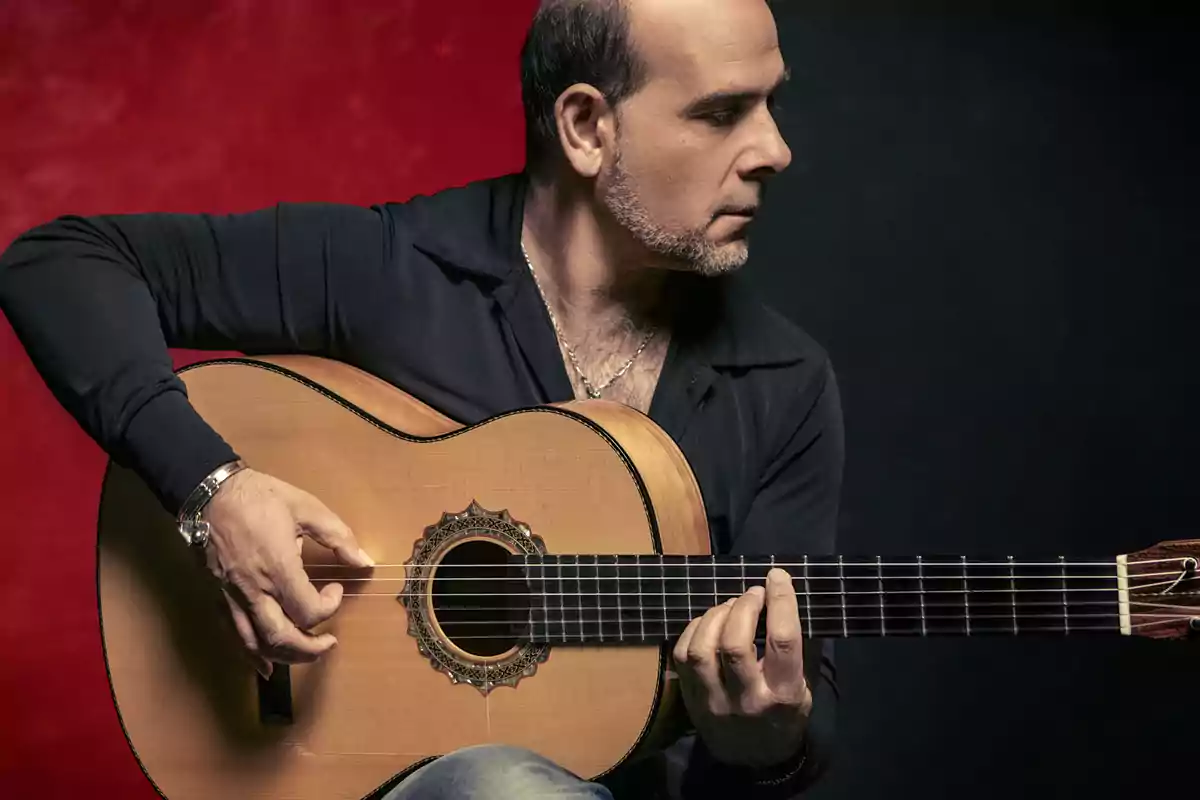 Hombre tocando una guitarra flamenca con fondo rojo y negro Hombre tocando una guitarra flamenca con fondo rojo y negro