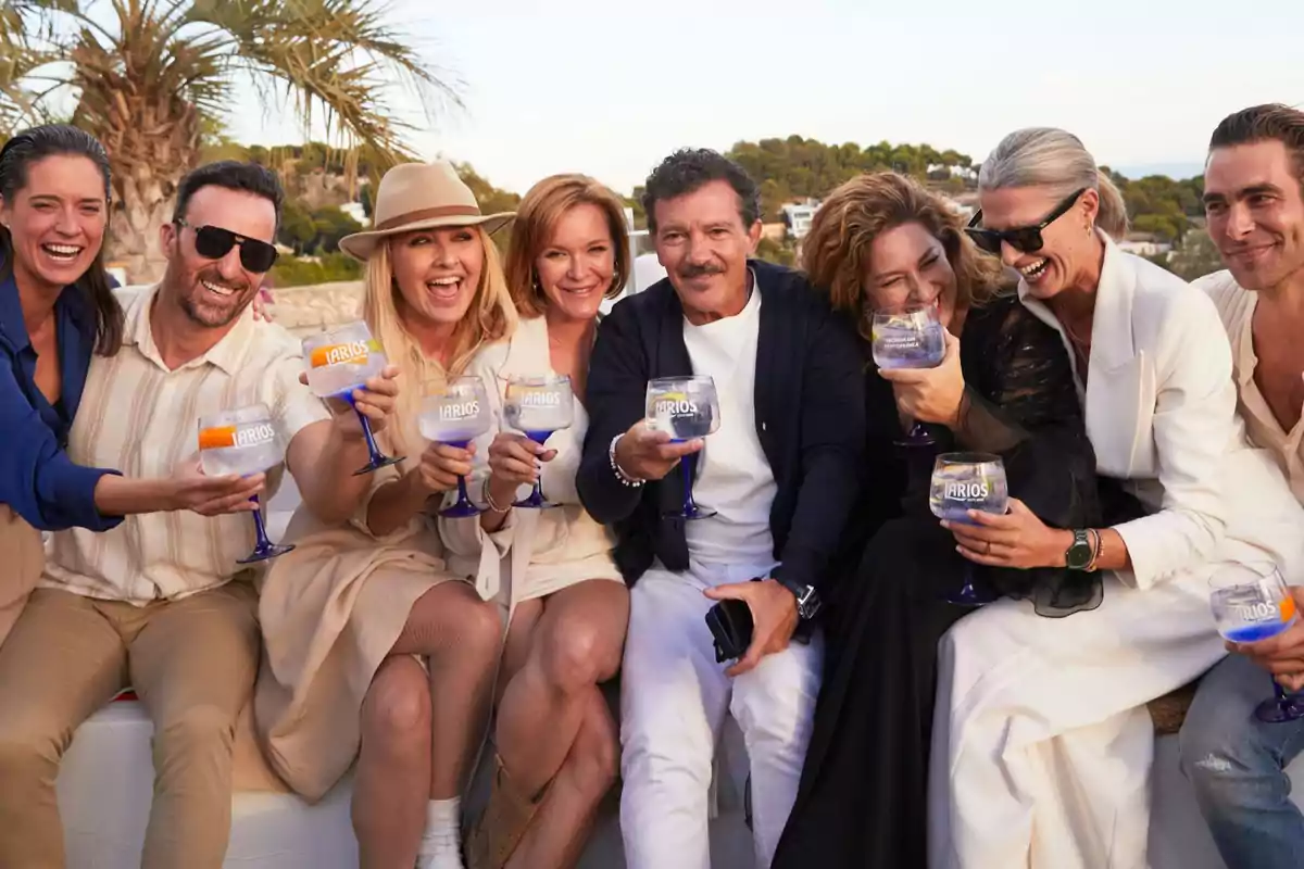 Un grupo de personas sonríe y brinda con copas grandes al aire libre en un ambiente soleado y relajado Un grupo de personas sonríe y brinda con copas grandes al aire libre en un ambiente soleado y relajado