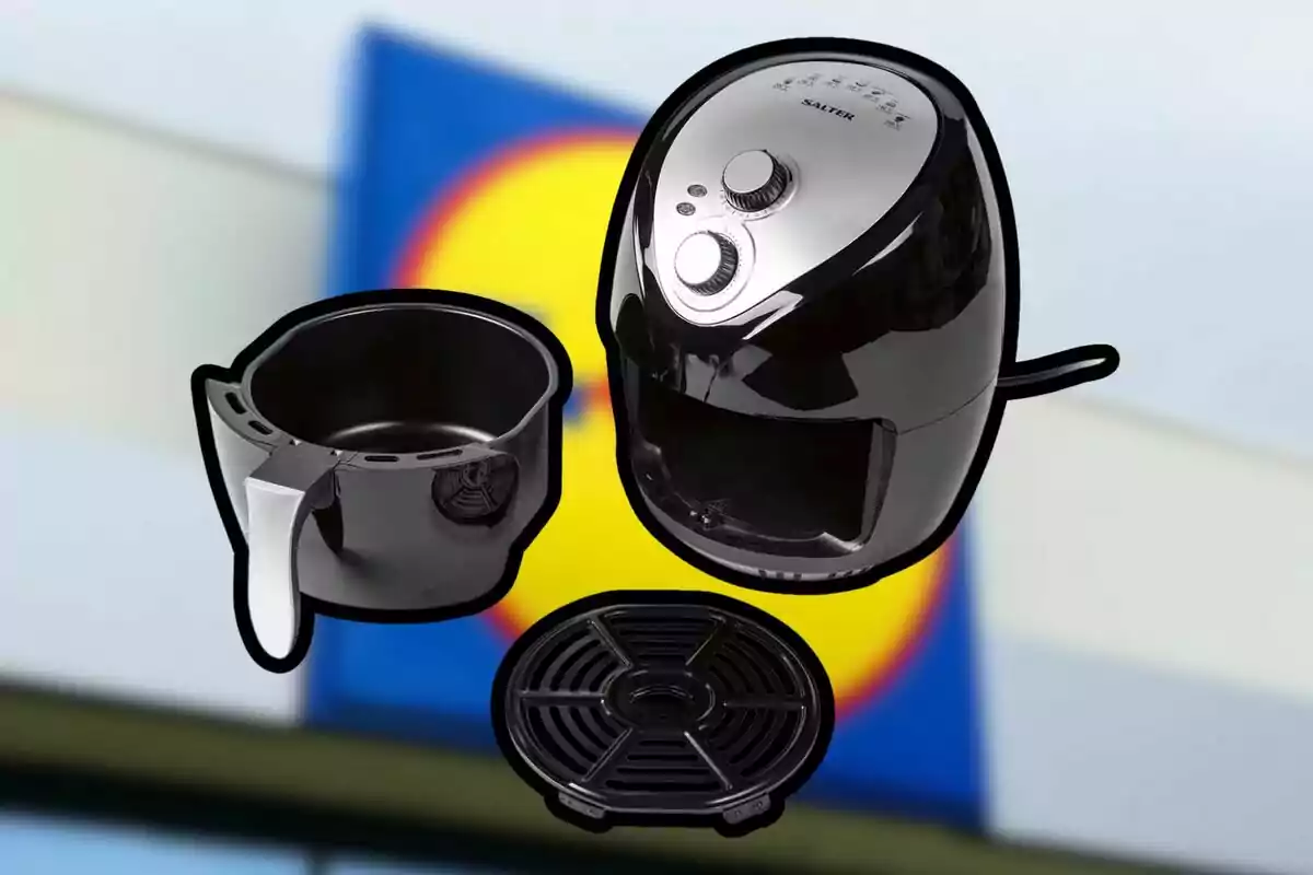 Freidora de aire negra con sus accesorios frente a un fondo desenfocado de un letrero de supermercado Freidora de aire negra con sus accesorios frente a un fondo desenfocado de un letrero de supermercado