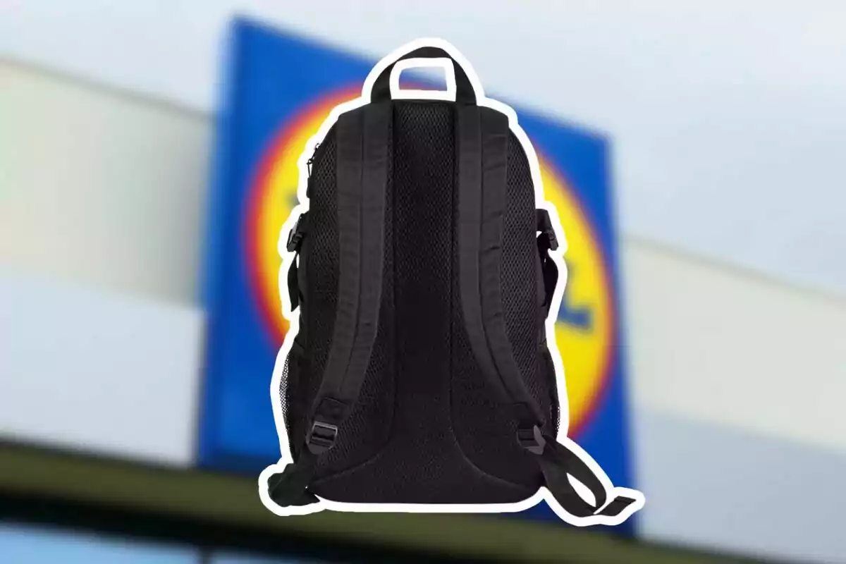 Mochila negra vista desde atrás con tirantes acolchados frente a un fondo borroso de un letrero de tienda Mochila negra vista desde atrás con tirantes acolchados frente a un fondo borroso de un letrero de tienda