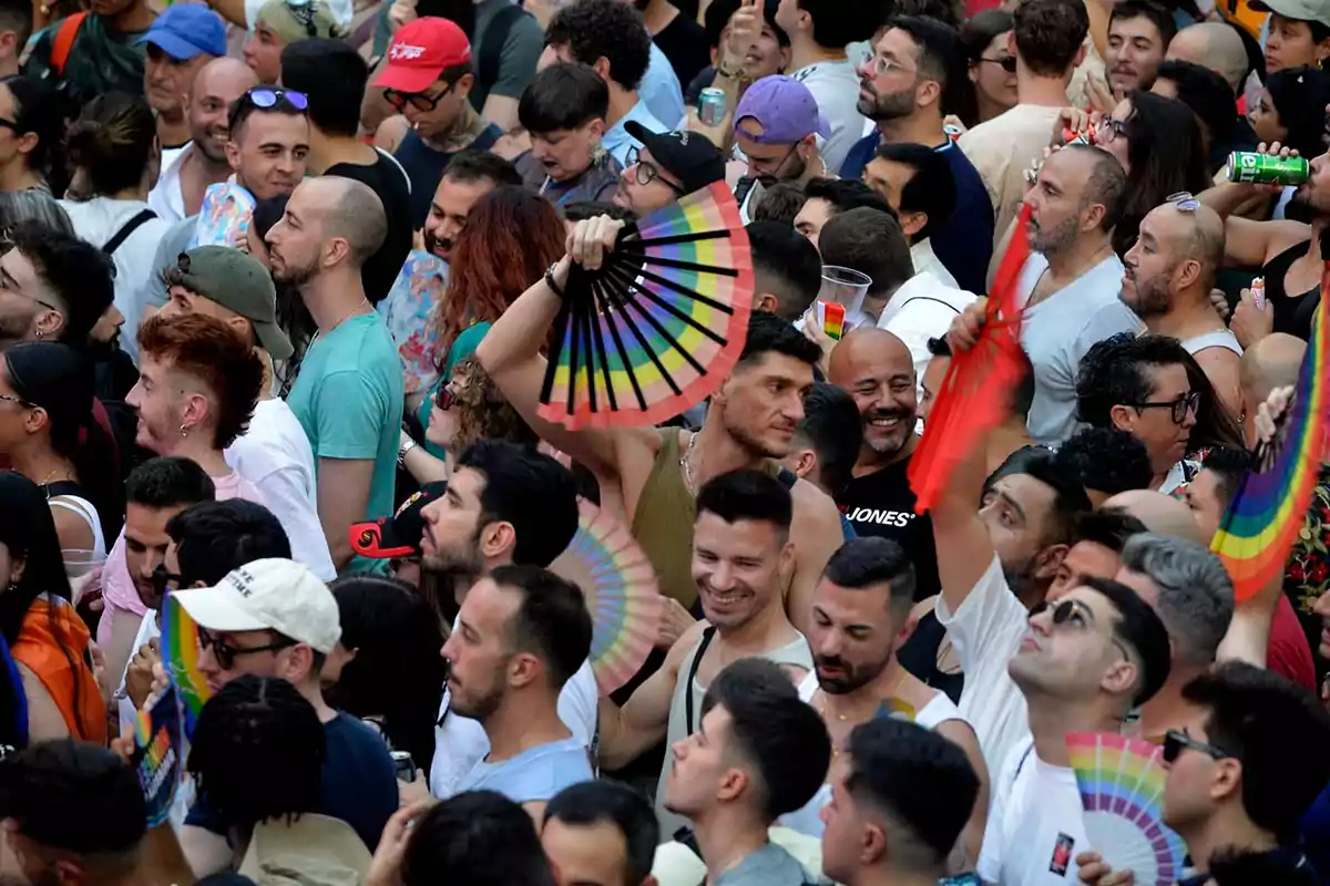 Multitud de personas celebrando en un evento al aire libre con abanicos de colores y ambiente festivo Multitud de personas celebrando en un evento al aire libre con abanicos de colores y ambiente festivo