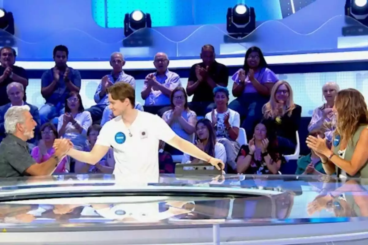 Dos concursantes se dan la mano en el centro de un plató de televisión mientras el público de 'Pasapalabra' aplaude desde las gradas. Dos concursantes se dan la mano en el centro de un plató de televisión mientras el público de 'Pasapalabra' aplaude desde las gradas.