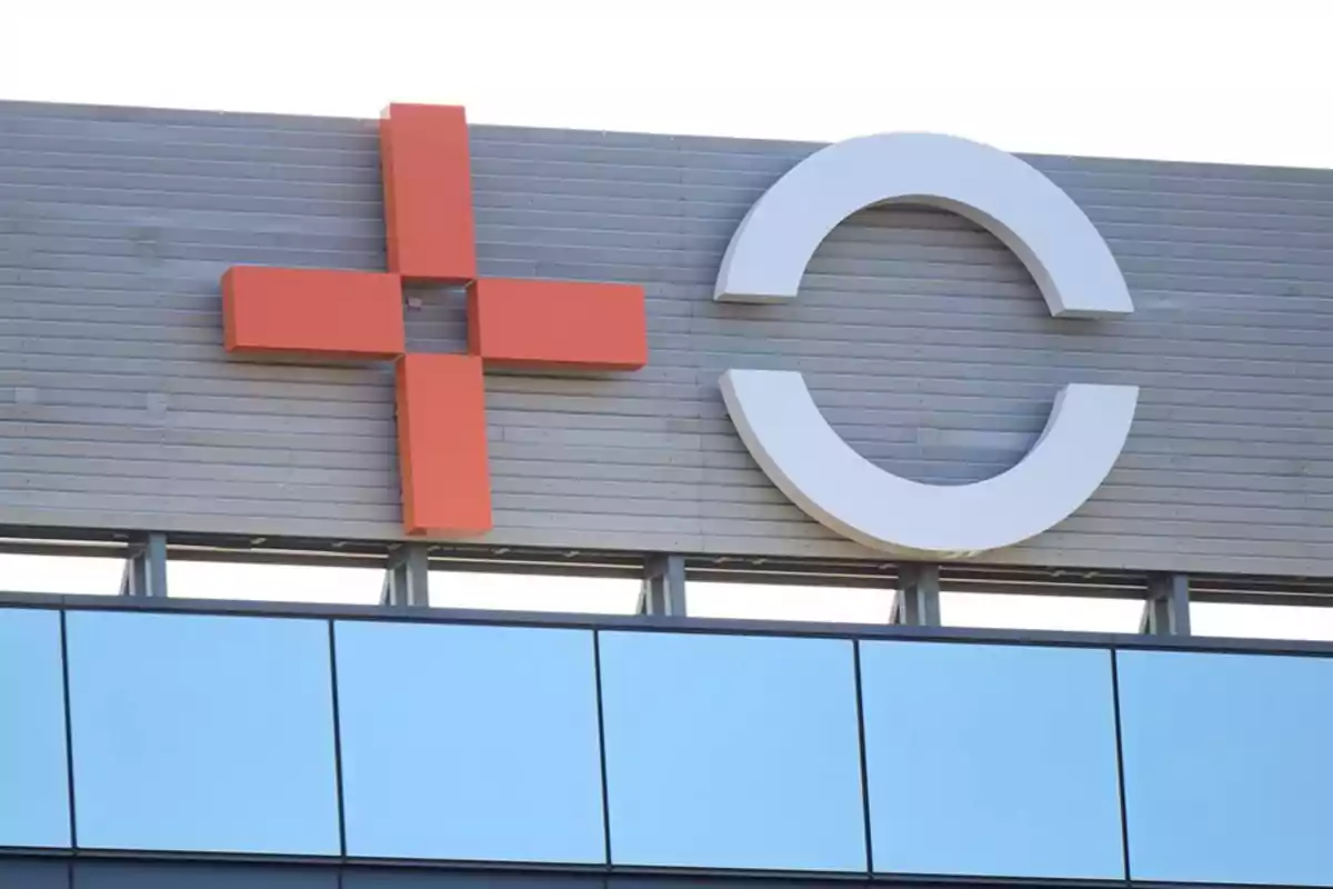 Logotipo de un hospital con una cruz roja y una letra C blanca sobre una pared gris Logotipo de un hospital con una cruz roja y una letra C blanca sobre una pared gris