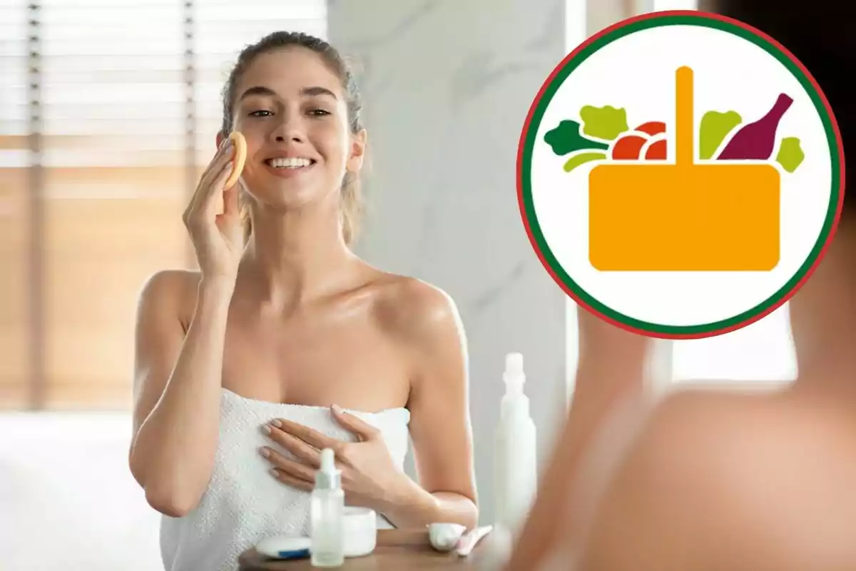 Mujer joven sonriente aplicando producto facial frente a un espejo con una toalla blanca y un icono de canasta de alimentos en la esquina superior derecha Mujer joven sonriente aplicando producto facial frente a un espejo con una toalla blanca y un icono de canasta de alimentos en la esquina superior derecha