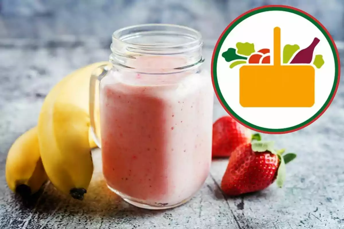 Vaso de licuado de fresa y plátano junto a frutas frescas y un icono de canasta de alimentos Vaso de licuado de fresa y plátano junto a frutas frescas y un icono de canasta de alimentos