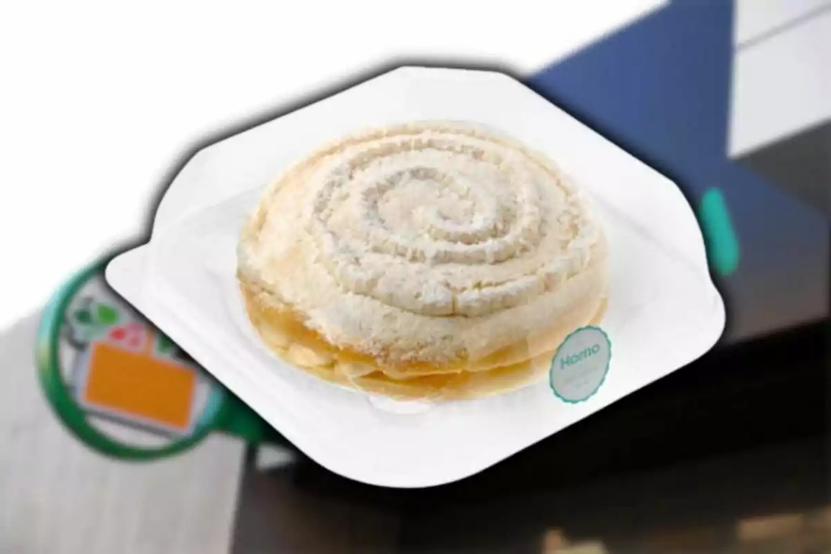 Un pan dulce tipo concha con forma de espiral sobre una charola blanca frente a una tienda de conveniencia. Un pan dulce tipo concha con forma de espiral sobre una charola blanca frente a una tienda de conveniencia.