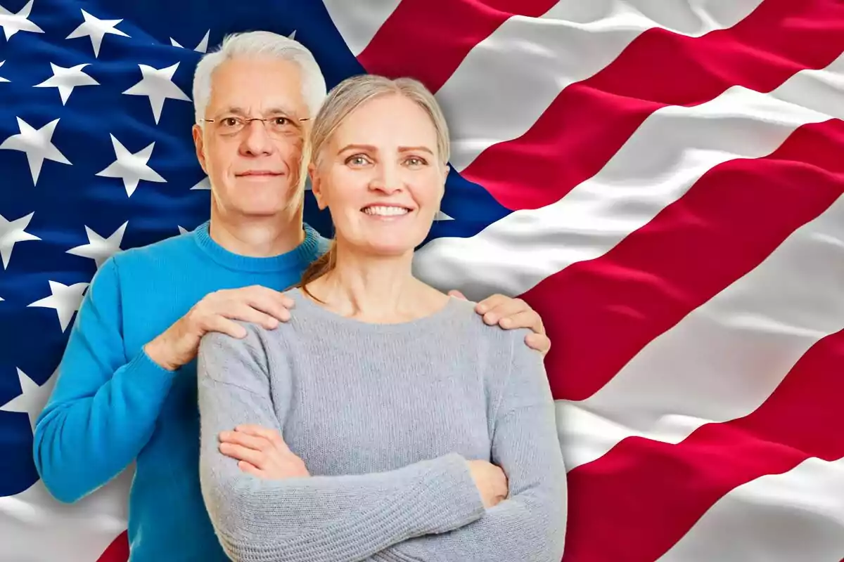 Pareja de personas mayores sonriendo frente a una bandera de Estados Unidos Pareja de personas mayores sonriendo frente a una bandera de Estados Unidos