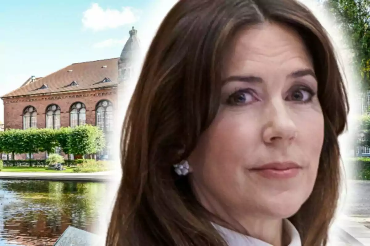 Mary de Dinamarca con expresión seria en primer plano y edificio antiguo de ladrillo con ventanas grandes al fondo junto a un estanque y árboles recortados.