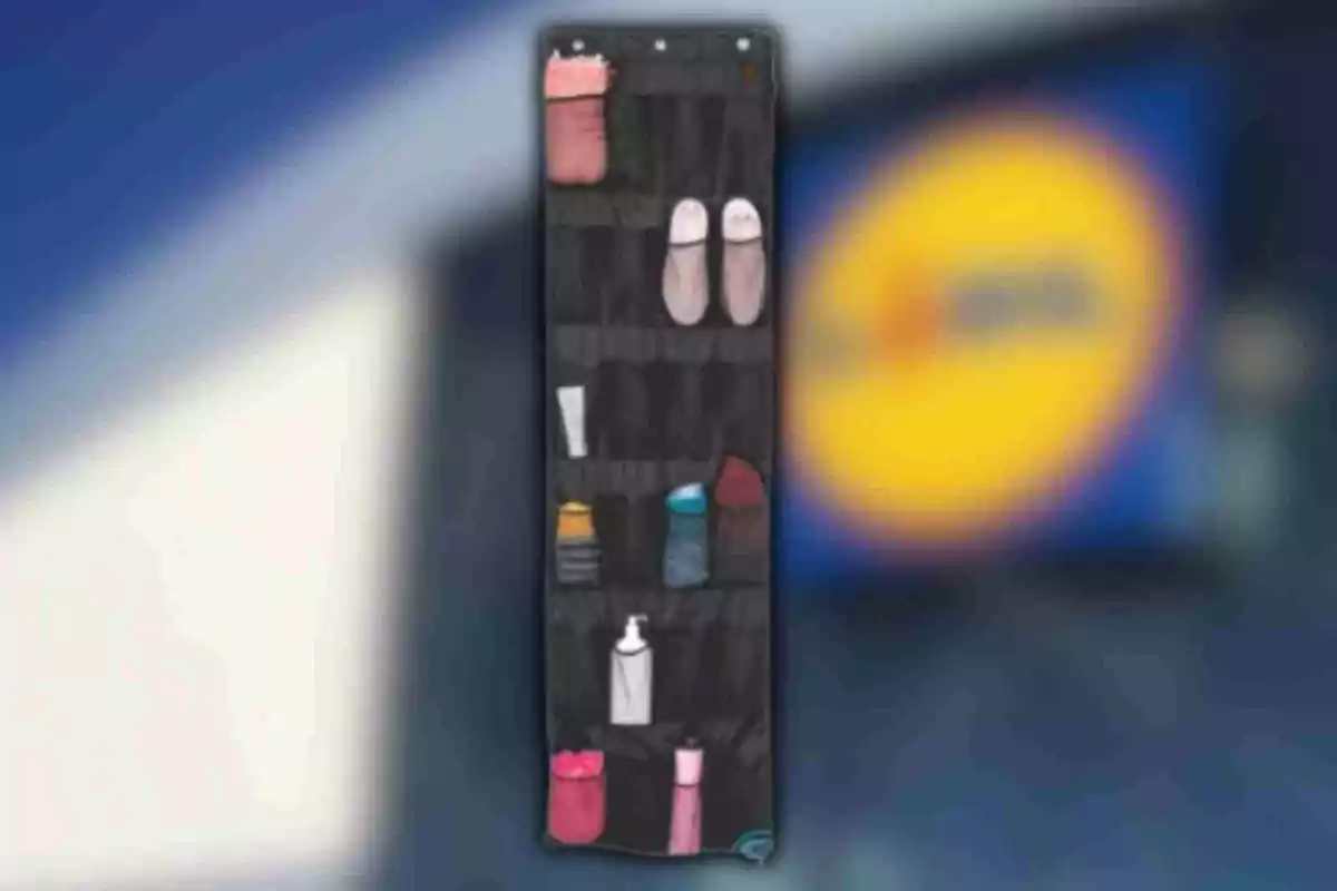 Organizador colgante negro con varios objetos como botellas, zapatos y frascos en sus compartimentos frente a un fondo desenfocado Organizador colgante negro con varios objetos como botellas, zapatos y frascos en sus compartimentos frente a un fondo desenfocado