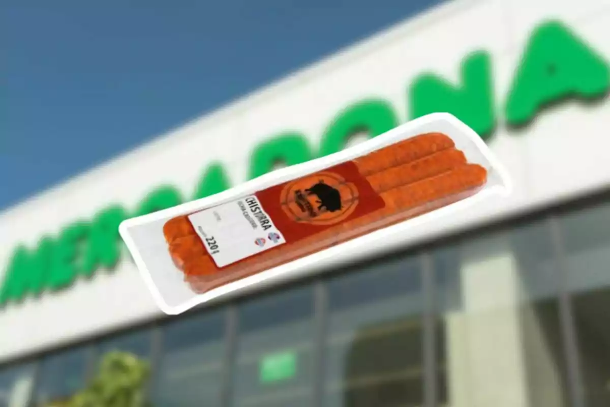 Paquete de chistorra en primer plano con una tienda de Mercadona desenfocada al fondo Paquete de chistorra en primer plano con una tienda de Mercadona desenfocada al fondo