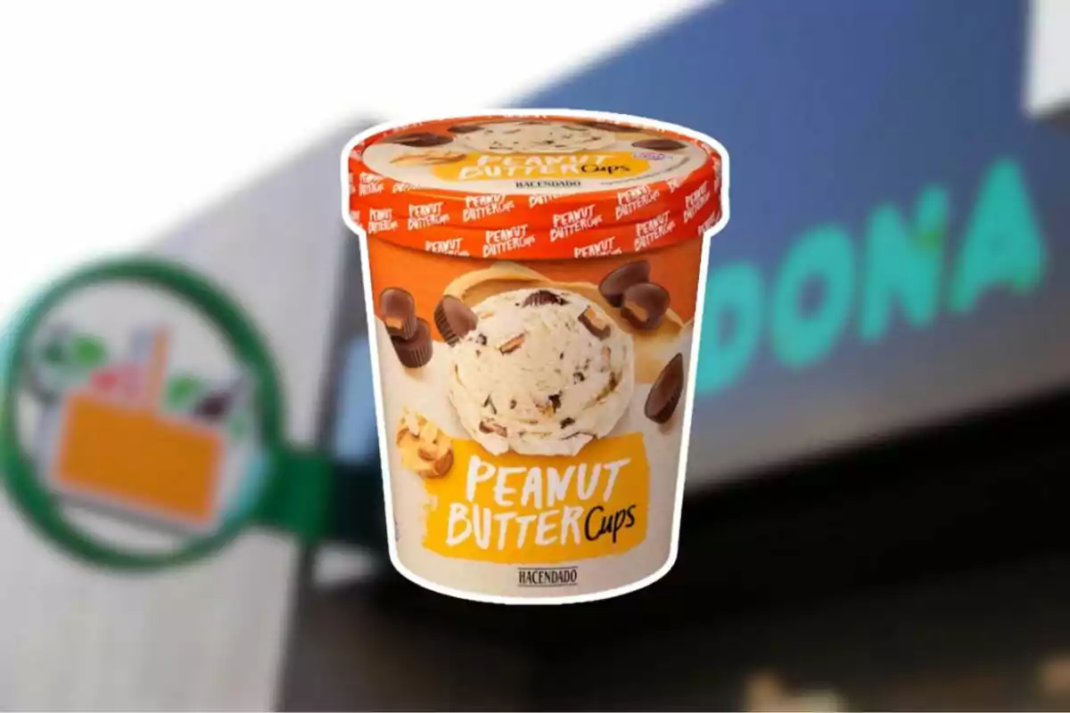 Helado de crema de cacahuete con trozos de chocolate de la marca Hacendado frente a un cartel borroso de Mercadona Helado de crema de cacahuete con trozos de chocolate de la marca Hacendado frente a un cartel borroso de Mercadona