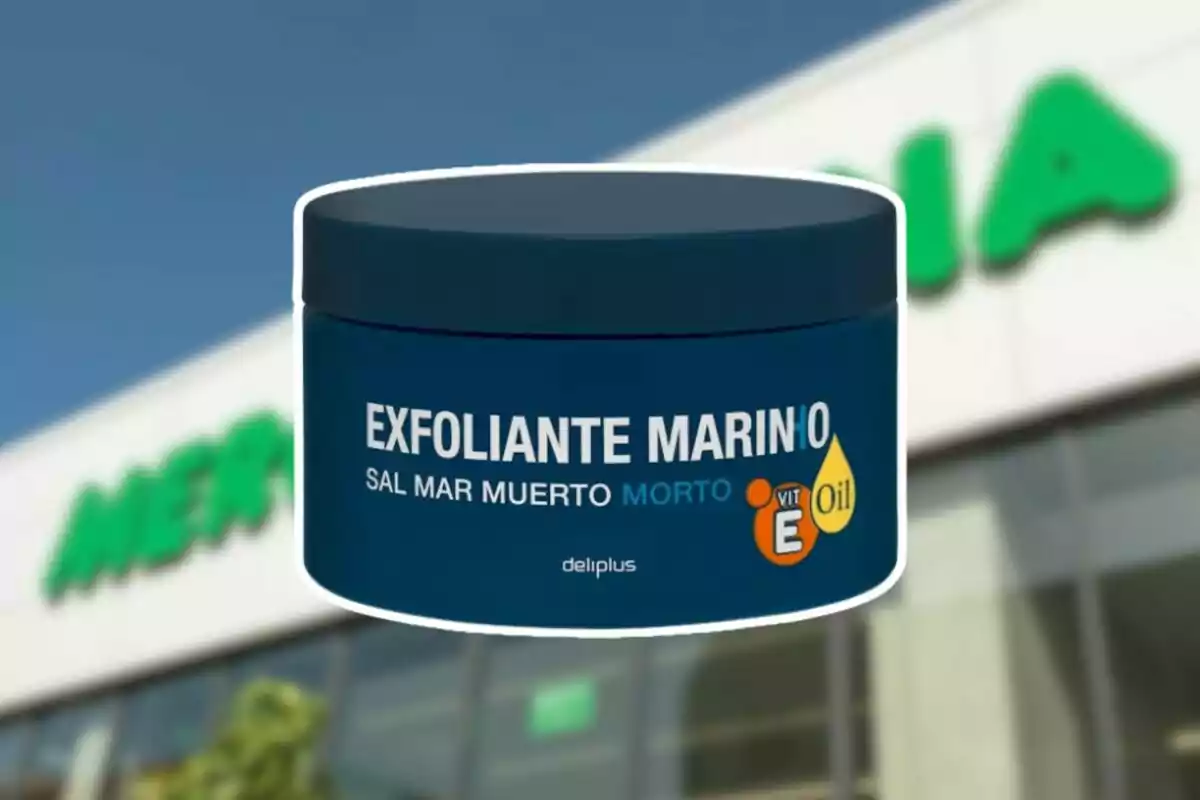 Envase azul de exfoliante marino con sal del Mar Muerto de la marca Deliplus frente a una tienda Mercadona desenfocada Envase azul de exfoliante marino con sal del Mar Muerto de la marca Deliplus frente a una tienda Mercadona desenfocada