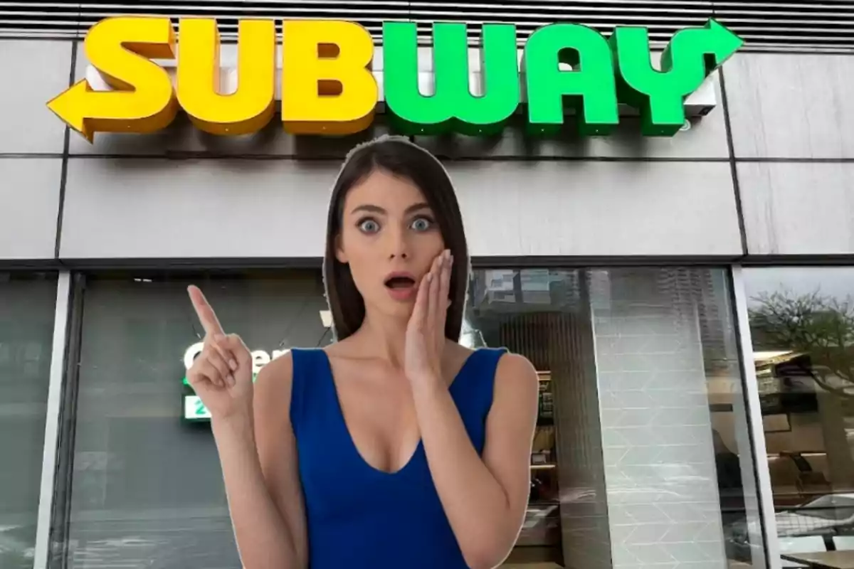 Mujer sorprendida señalando hacia el letrero de Subway en la entrada de un restaurante
