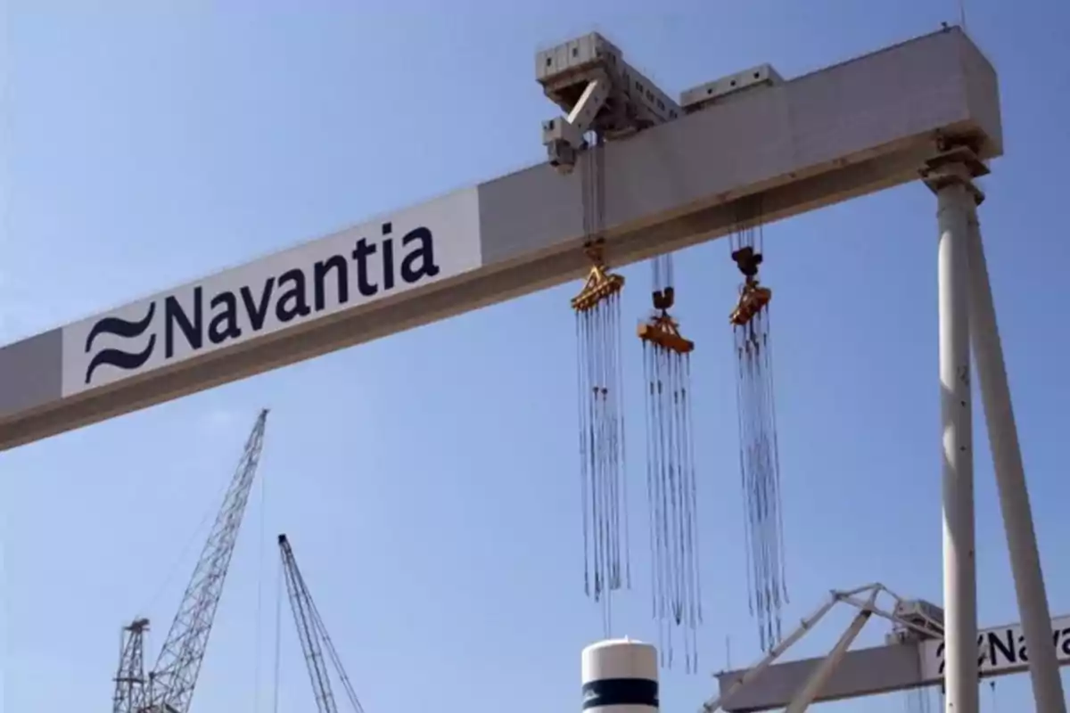 Grúa industrial de gran tamaño con el logo de Navantia en un astillero bajo un cielo despejado