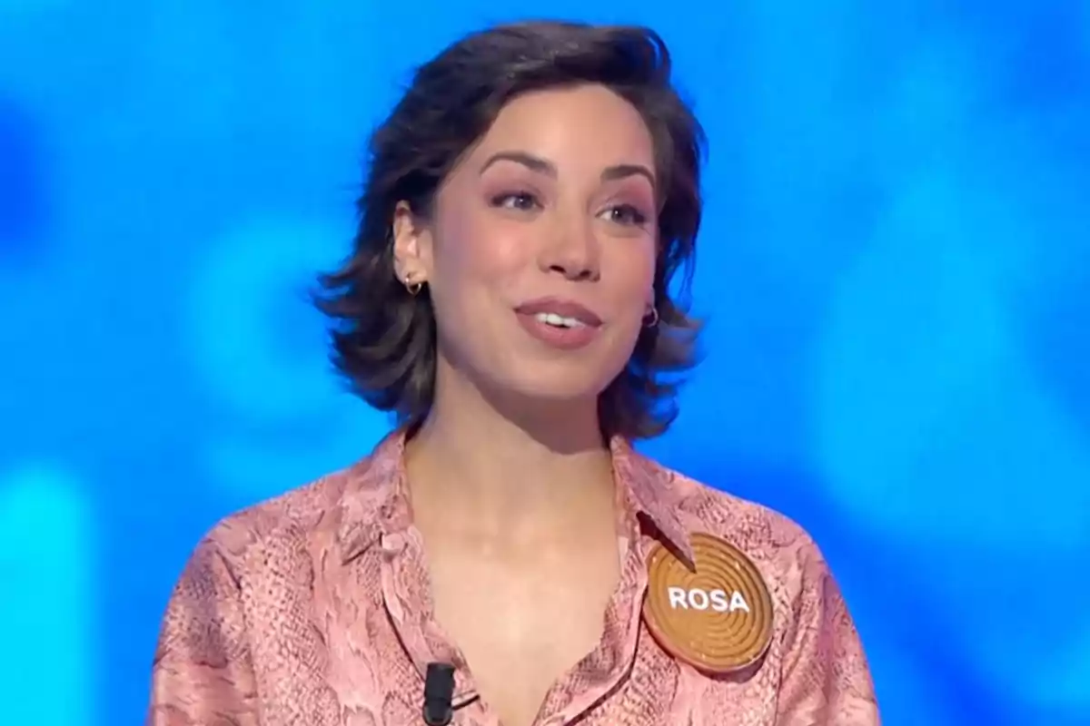 Rosa con camisa rosa y un pin que dice Rosa sobre un fondo azul. Captura de 'Pasapalabra' Rosa con camisa rosa y un pin que dice Rosa sobre un fondo azul. Captura de 'Pasapalabra'