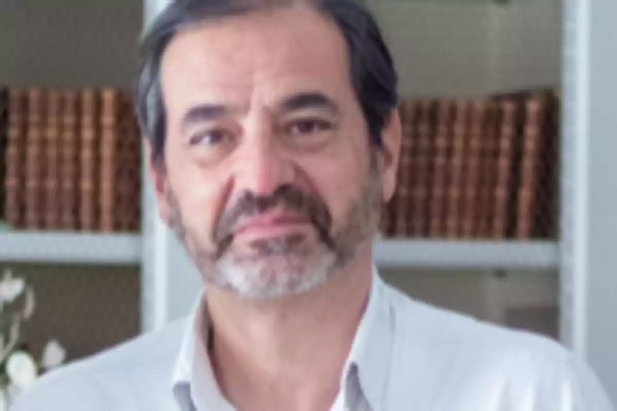 Hombre de mediana edad con barba y cabello canoso en una habitación con estanterías y libros al fondo Hombre de mediana edad con barba y cabello canoso en una habitación con estanterías y libros al fondo