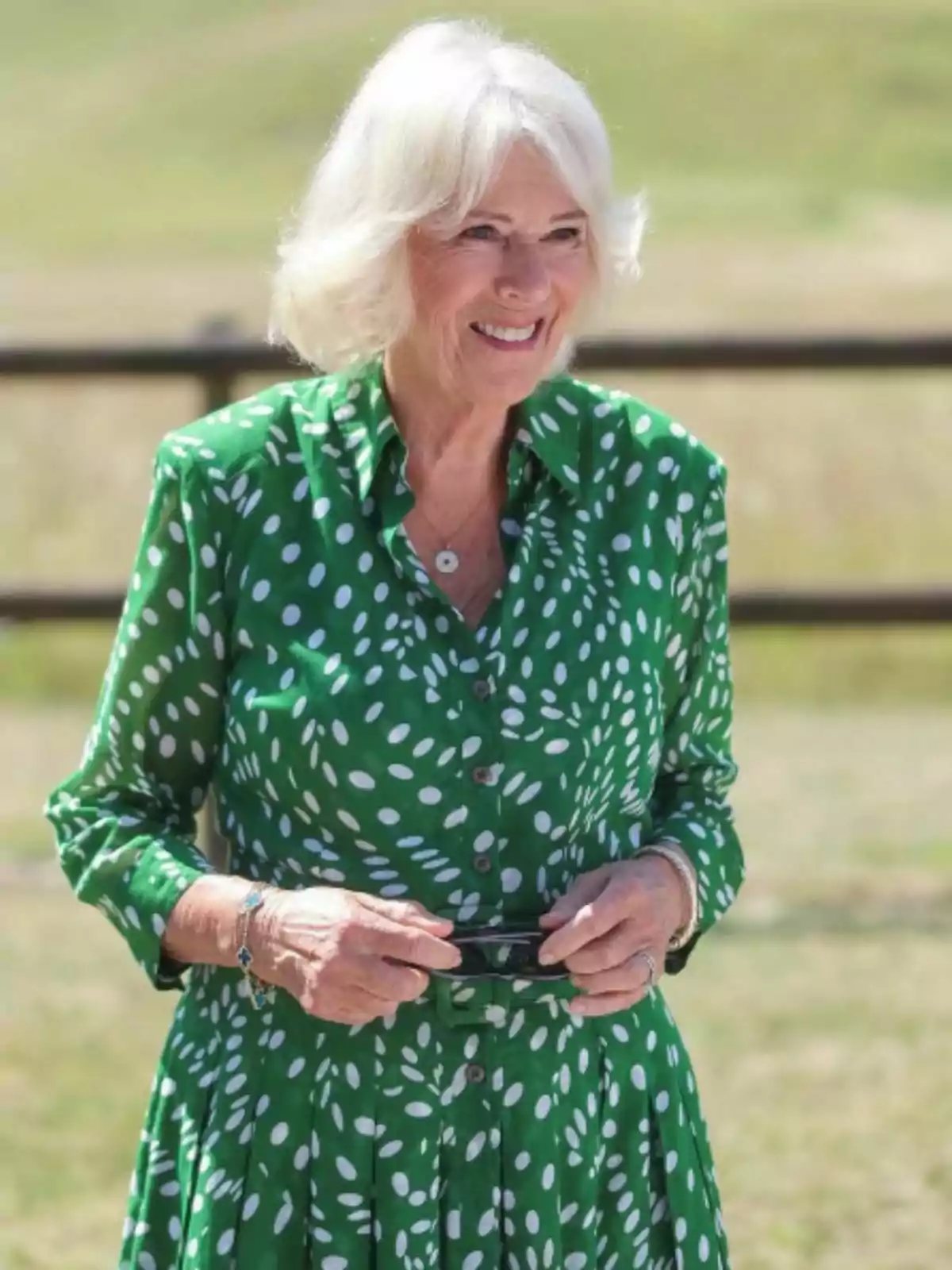 La reina Camila sonriente con vestido verde de lunares blancos en un entorno al aire libre La reina Camila sonriente con vestido verde de lunares blancos en un entorno al aire libre