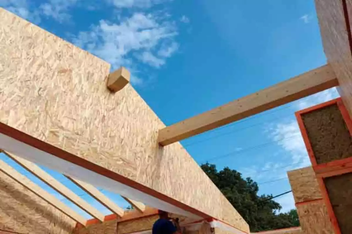 Construcción de una estructura de madera con paneles OSB bajo un cielo azul con algunas nubes Construcción de una estructura de madera con paneles OSB bajo un cielo azul con algunas nubes