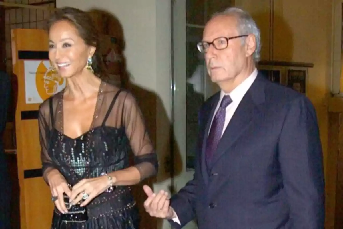 Una mujer con vestido elegante y un hombre con traje caminan juntos en un evento social en interiores Una mujer con vestido elegante y un hombre con traje caminan juntos en un evento social en interiores