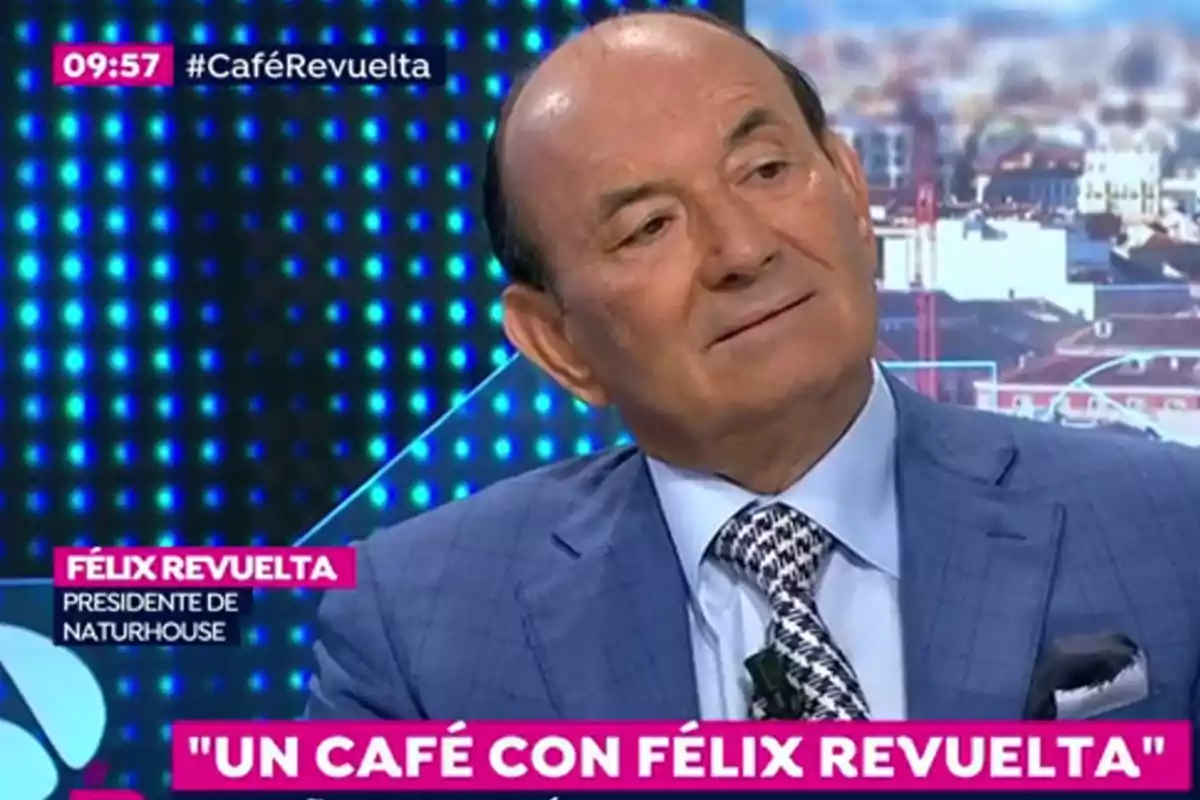 Hombre de traje azul claro y corbata estampada participando en una entrevista televisiva titulada Un café con Félix Revuelta Hombre de traje azul claro y corbata estampada participando en una entrevista televisiva titulada Un café con Félix Revuelta