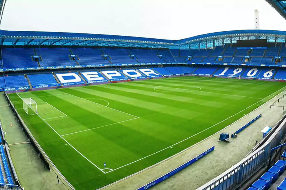 Estadio de fútbol vacío con gradas azules y césped bien cuidado Estadio de fútbol vacío con gradas azules y césped bien cuidado