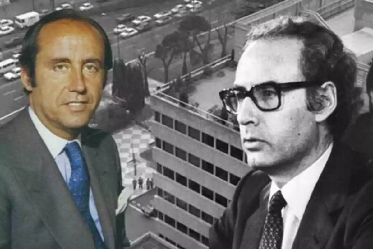 Dos hombres con traje en primer plano, uno de ellos con gafas, con un edificio y una avenida al fondo
