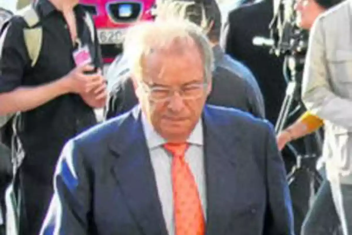 Hombre mayor con gafas y corbata naranja caminando entre varias personas en un entorno urbano Hombre mayor con gafas y corbata naranja caminando entre varias personas en un entorno urbano