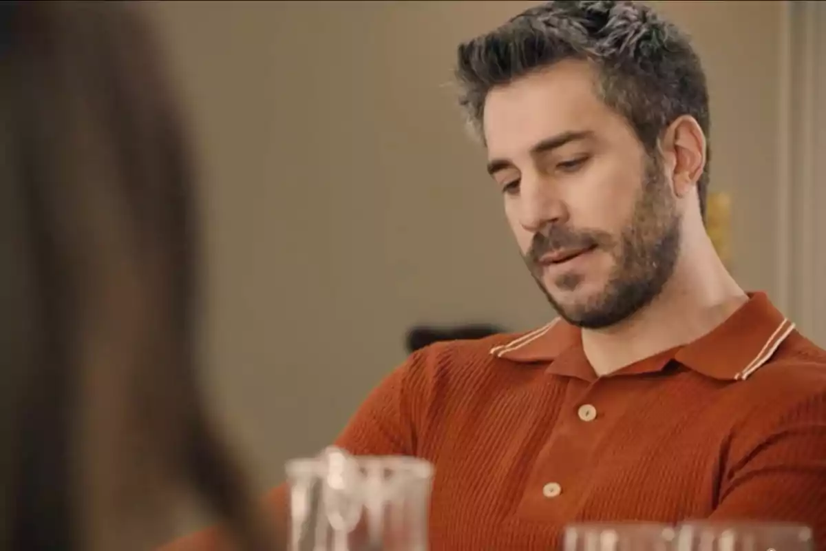 Andrés con expresión seria usando una camisa polo naranja sentado en una mesa. Captura de 'Sueños de libertad' Andrés con expresión seria usando una camisa polo naranja sentado en una mesa. Captura de 'Sueños de libertad'