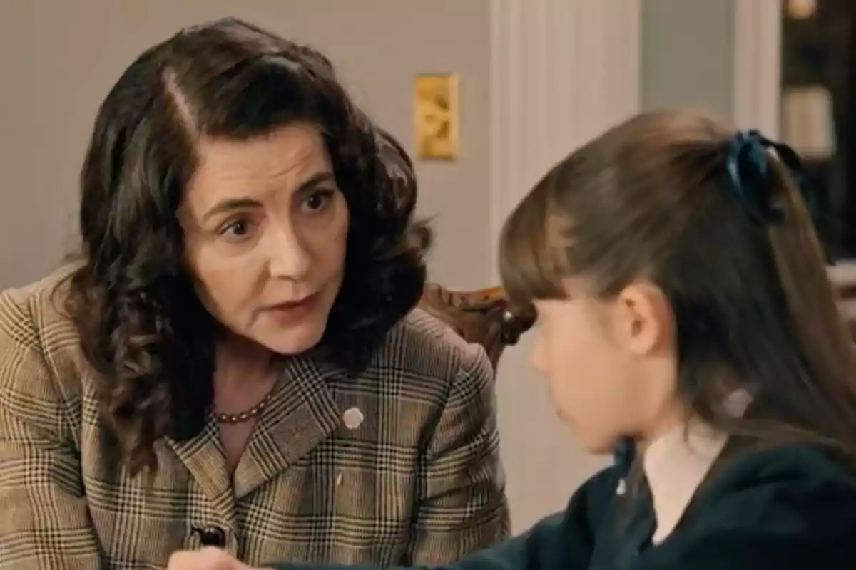 Digna habla con Julia que lleva el cabello recogido con un listón azul en un ambiente interior. Captura de 'Sueños de libertad' Digna habla con Julia que lleva el cabello recogido con un listón azul en un ambiente interior. Captura de 'Sueños de libertad'