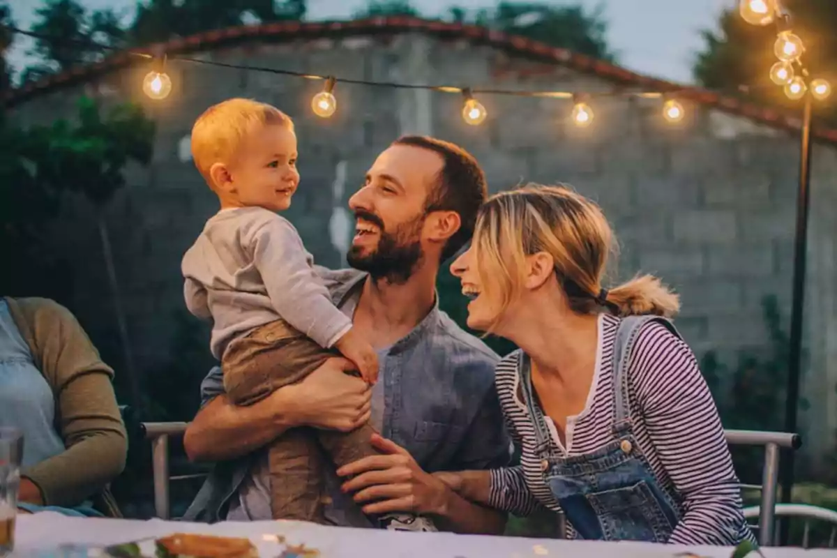 Familia disfrutando de una cena al aire libre con luces colgantes y sonrisas