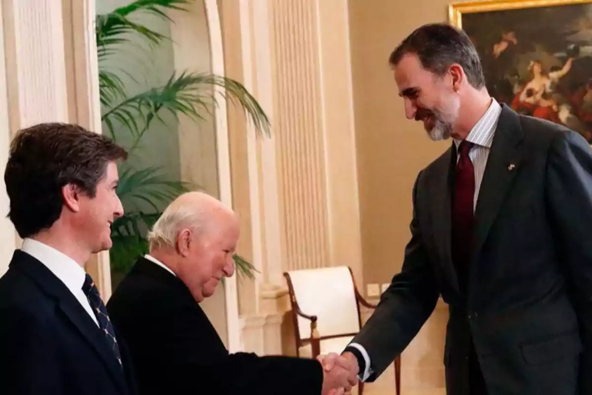 Tres hombres vestidos de traje se saludan cordialmente en una sala elegante Tres hombres vestidos de traje se saludan cordialmente en una sala elegante
