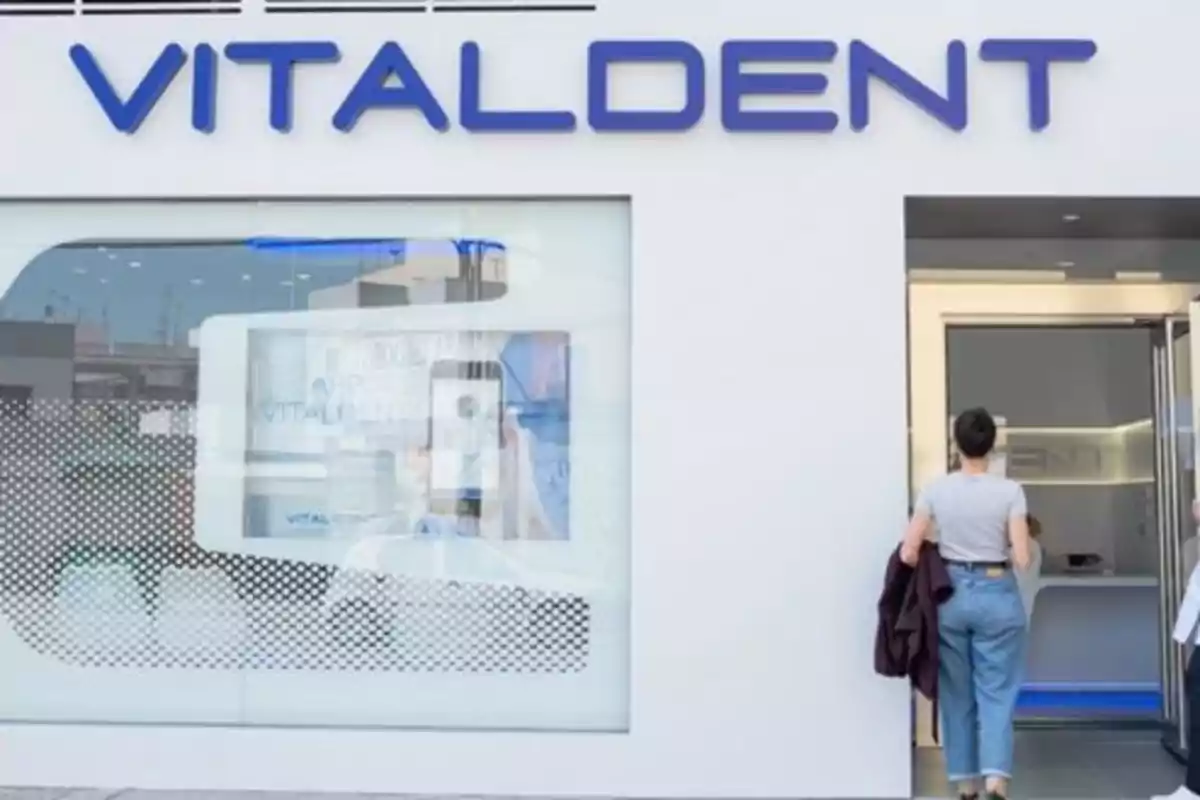 Fachada de una clínica dental Vitaldent con una persona entrando por la puerta