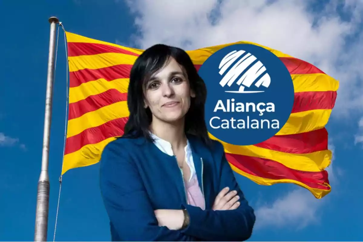 Mujer de cabello oscuro con los brazos cruzados frente a una bandera catalana ondeando y un logotipo de Aliança Catalana sobre un cielo azul con nubes